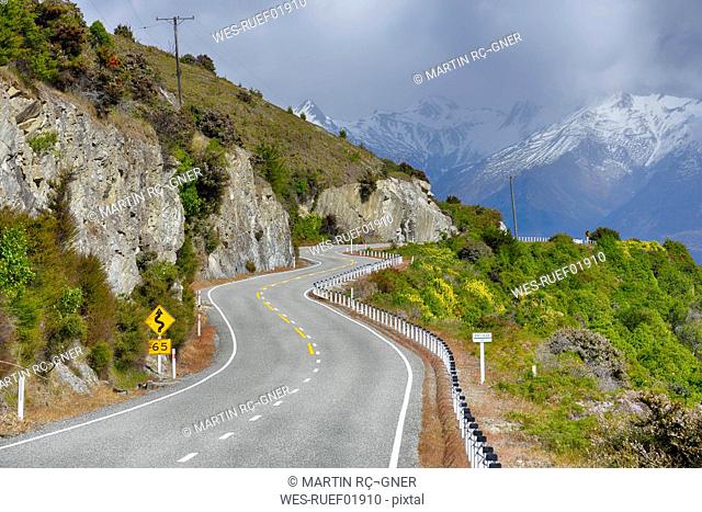 New Zealand, South Island, winding road in landscape along Lake Hawea with Southern Alps in the background