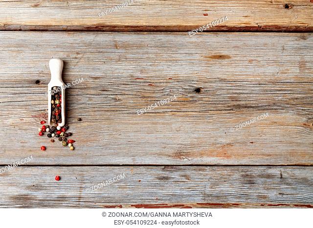 Multicolored Pepper peas in a measuring spoon. wooden background