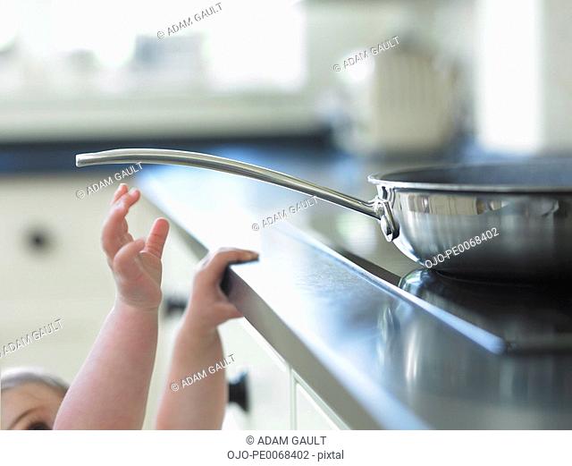 Baby reaching for hot frying pan on stove