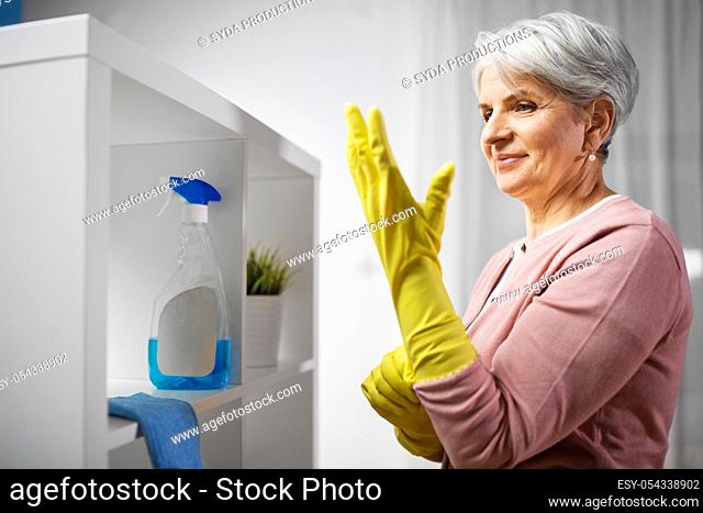 senior woman putting protective rubber gloves on