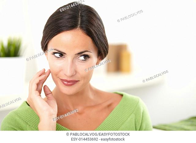 Young confident caucasian woman with hand on face looking away at indoors - copy space