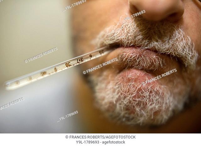 Middle-aged man with oral thermometer in his mouth