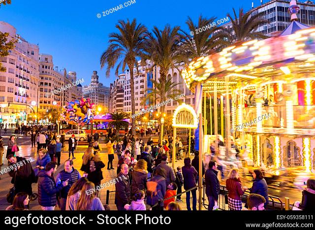 Valencia, Spain - Dec 16, 2017: People having fun in christmas spirit on Christmas fair with carousel on Modernisme plaza of the city hall of Valencia on 16th...