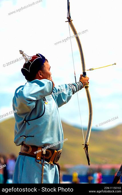 Ulaanbaatar, Mongolia - June 11, 2007: An arrow flying mid-air after launched by a male archer in traditional garb at the Naadam Festival archery competition