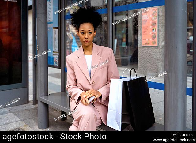 Thoughtful businesswoman sitting with shopping bags on bench