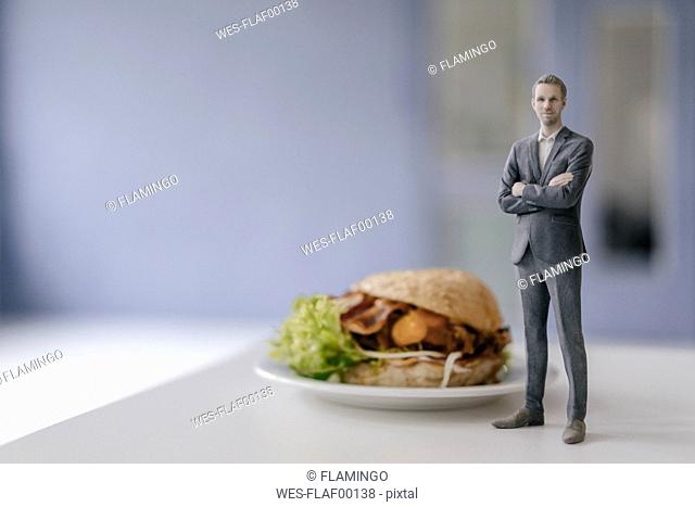 Miniature businessman figurine standing next to fast food