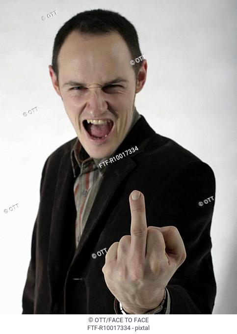 Young man making obscene hand gesture, mouth open