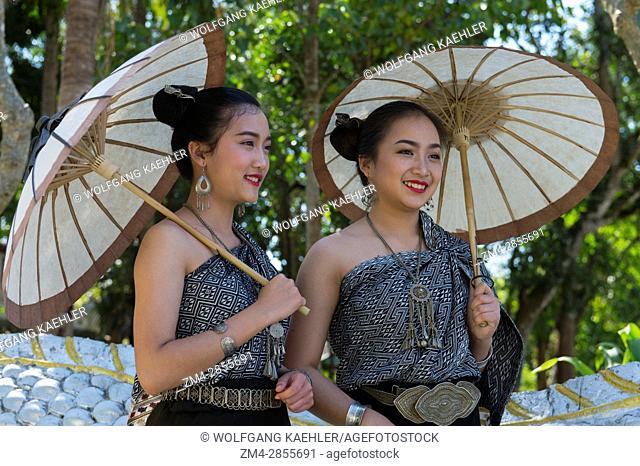 Two high school girls in traditional dresses and with parasols posing on the staircase of a temple in the UNESCO world heritage town of Luang Prabang in Central...