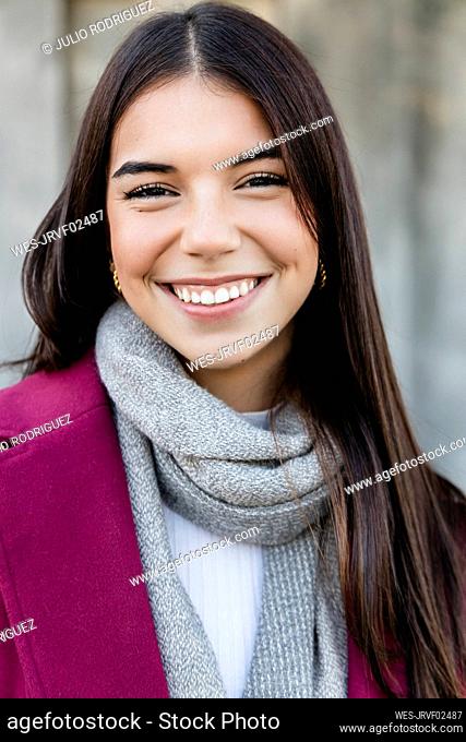 Happy young woman with long brown hair wearing scarf