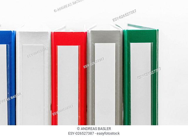 Closeup of group of colourful folders in a row on the left side of white background