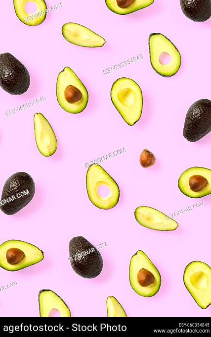 Avocado. Background made from isolated Avocado pieces on pink background. Flat lay of fresh ripe avocados and avacado pieces
