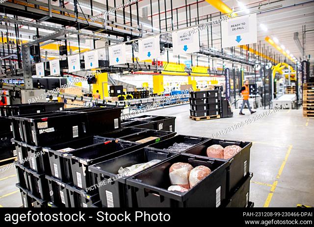 07 December 2023, Lower Saxony, Großenkneten: Black transport boxes containing various items are ready for storage at Amazon's new logistics center at the...