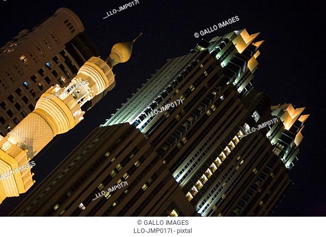 Illuminated mosque in front of highrise buildings at night, diagonal view  Dubai, United Arab Emirates