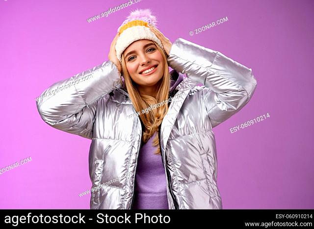 Tender romantic attractive blond female enjoying winter ski resort vacation having fun look pleased smiling broadly tilting head touching hat wearing silver...