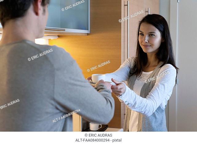 Woman handing man cup of coffee