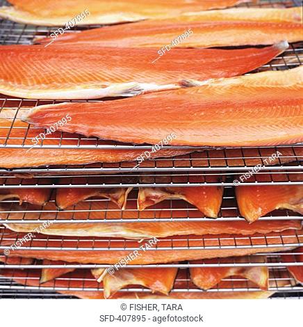 Sides of salmon on racks in a smoking oven