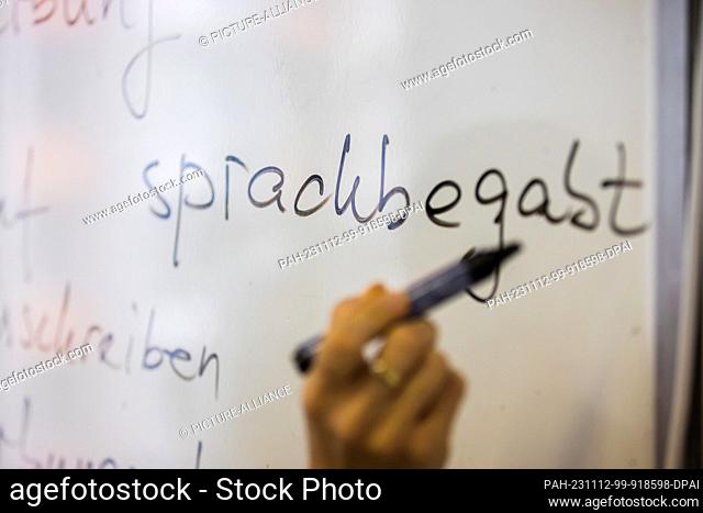 09 November 2023, Berlin: In a German course at a Berlin language school, a teacher writes the word ""sprachbegabt"" on the blackboard
