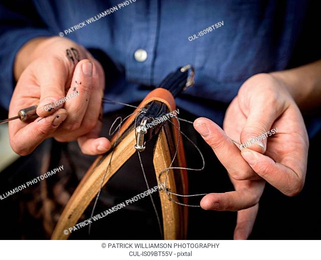 Leatherworker stitching handbag in workshop, close up of hands