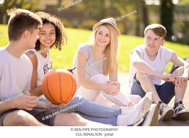 Four young adult basketball players sitting chatting