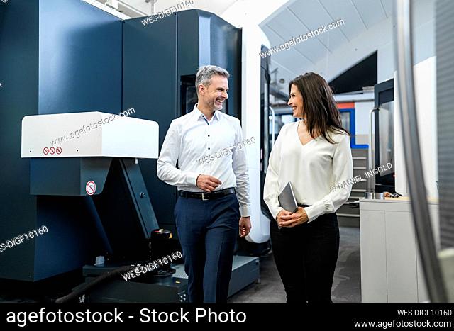 Happy businessman and businesswoman walking in a factory