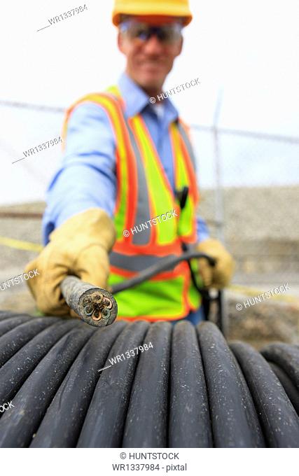 Engineer at electric power plant examining electrical distribution wire at storage area