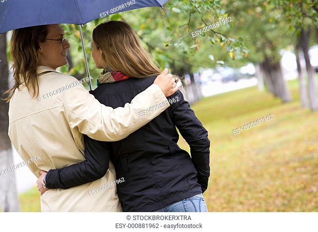 Rear view of affectionate couple walking under umbrella