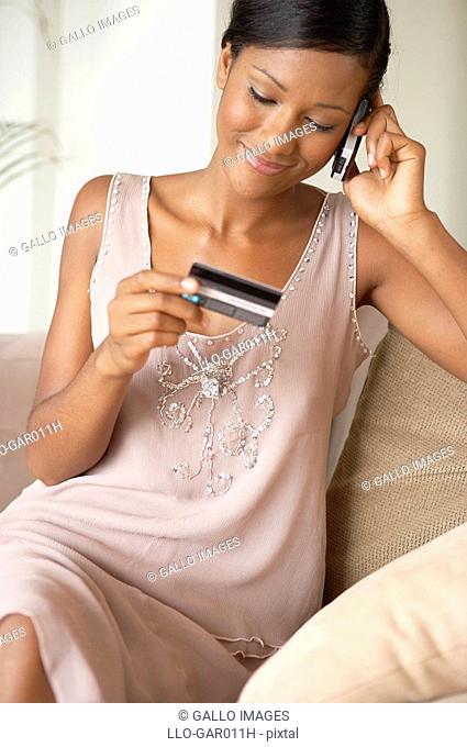Young African Woman on a Cell Phone Holding a Credit Card  Cape Town, Western Cape Province, South Africa