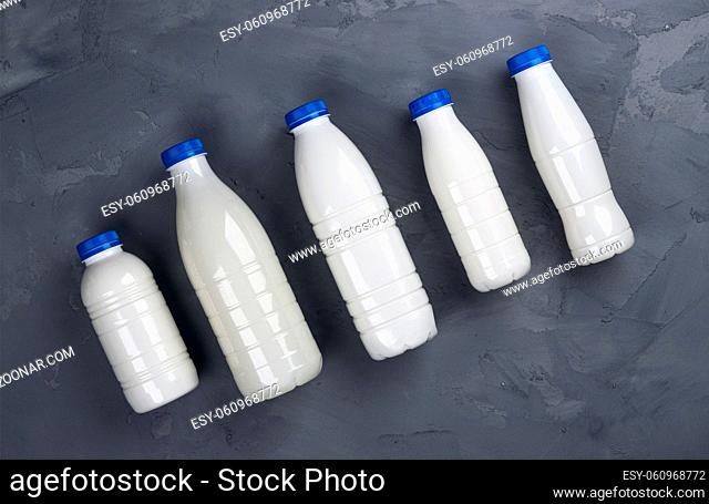 Dairy products packaging, collection of milk bottles on gray stone background, top view, flat lay