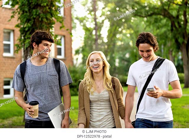 Three friends walking and talking on the university campus; Edmonton, Alberta, Canada