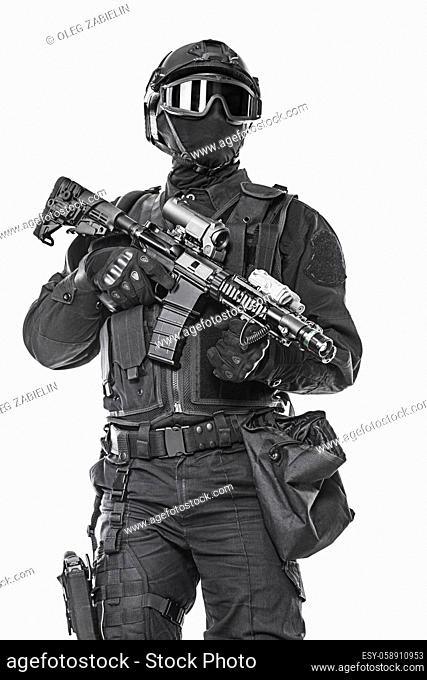 Studio shot of swat operator with assault rifle. Tactical helmet gloves, eyewear. Security forces concept. Low angle view
