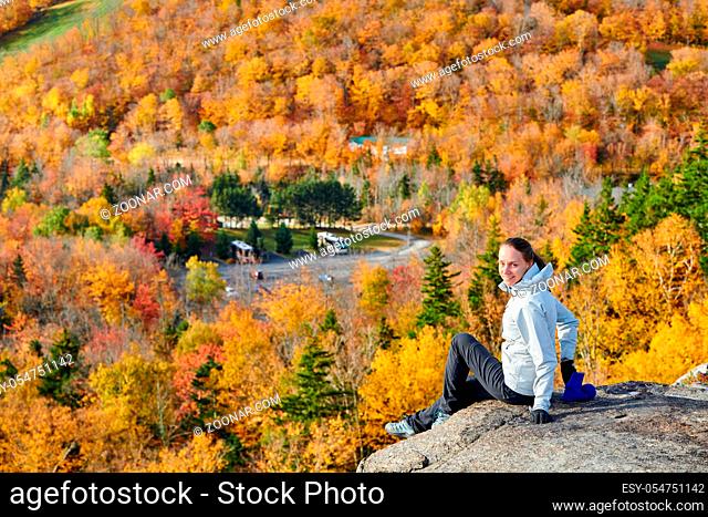Woman hiking at Artist's Bluff in autumn. Fall colours in Franconia Notch State Park. White Mountain National Forest, New Hampshire, USA