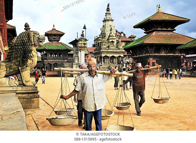 Wokers walk by with balance soil carrier in Durbar Square UNESCO World heritage site
