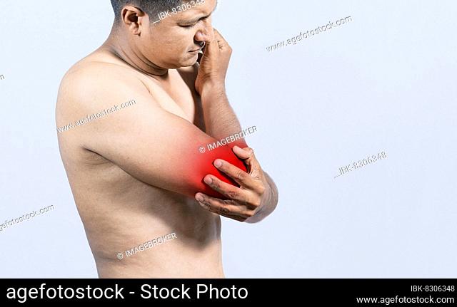 Person with elbow pain, concept of a people with elbow pain from rheumatism, shirtless man massaging sore elbow, man with elbow cramp
