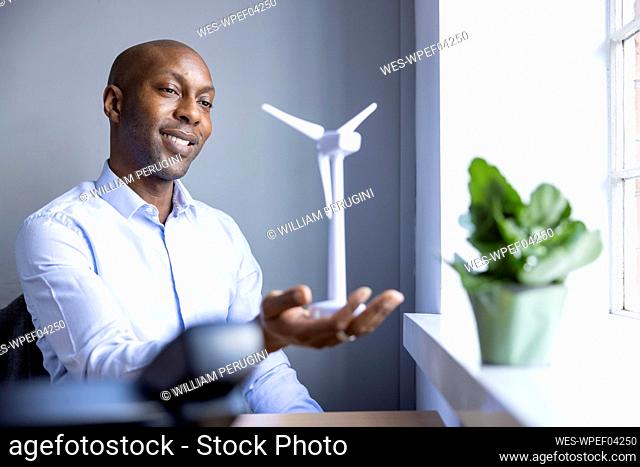 Male entrepreneur looking at wind turbine model at office