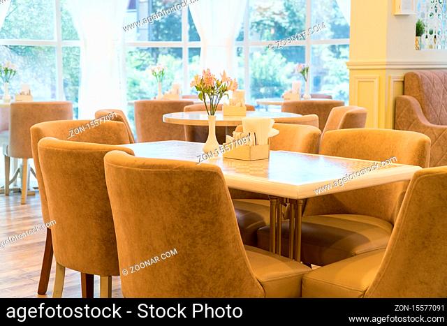 modern restaurant interior with windows and flowers. cafe room illuminated by sunlight