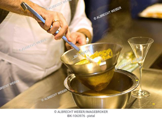 Cooking lesson, making spiced oranges, orange syrup being strained through a sieve, Germany, Europe