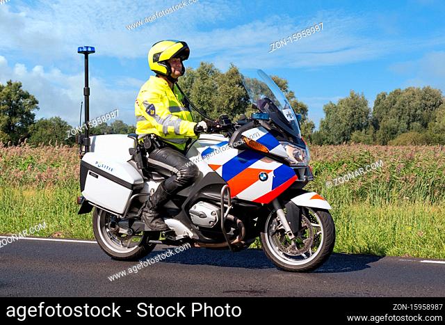 Urk, The Netherlands- September 08, 2012: Motorcycle policeman riding in rural landscape near Urk, The Netherlands