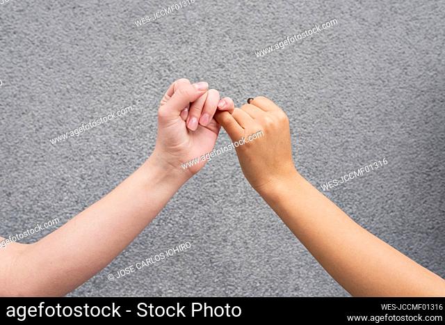 Hands of two women making pinky promise