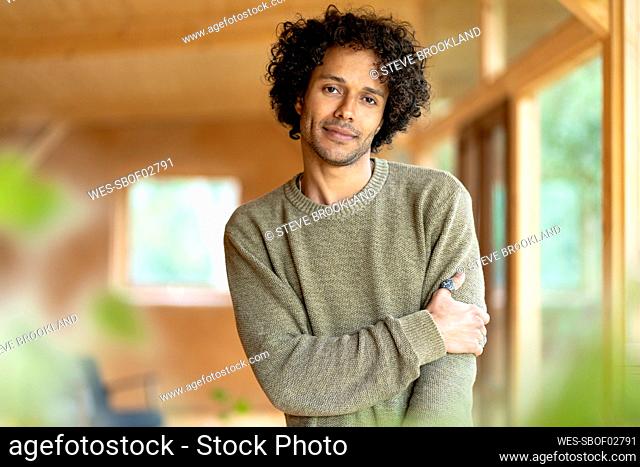 Curly hair man staring while standing at spacious room