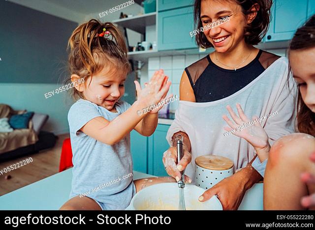 Mom and two daughters cook together in the kitchen