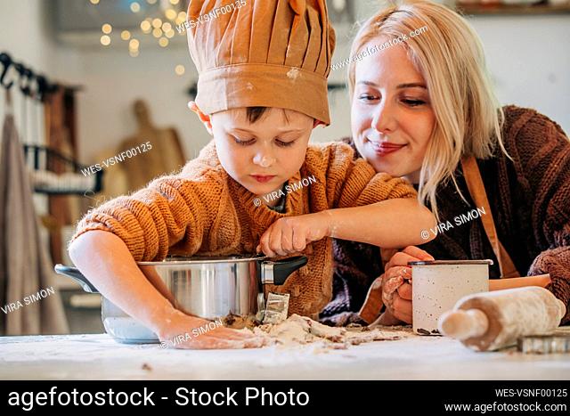 Smiling woman with son preparing cookies at home