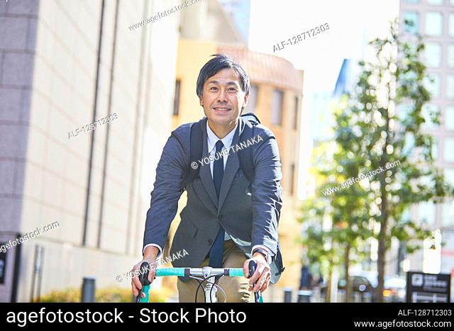 Middle Aged Japanese Businessman Riding A Bicycle