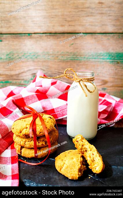 Milk and cookies on the bright napkin on the wooden tray