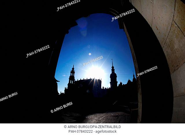 The Katholische Hofkirche (Catholic Church of the Royal Court of Saxony, L) and the Hausmannsturm sillhouette against the sun pictured through an arch of the...