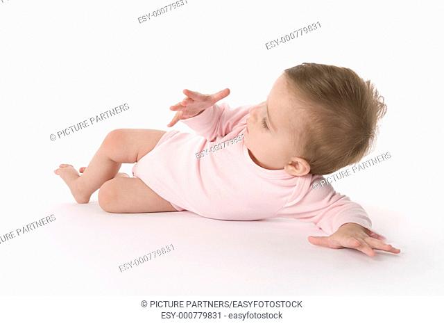 Baby girl lying on the floor looking at her own hand