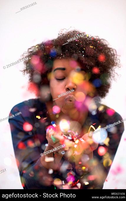 happy young woman celebrating new years eve party while blowing confetti