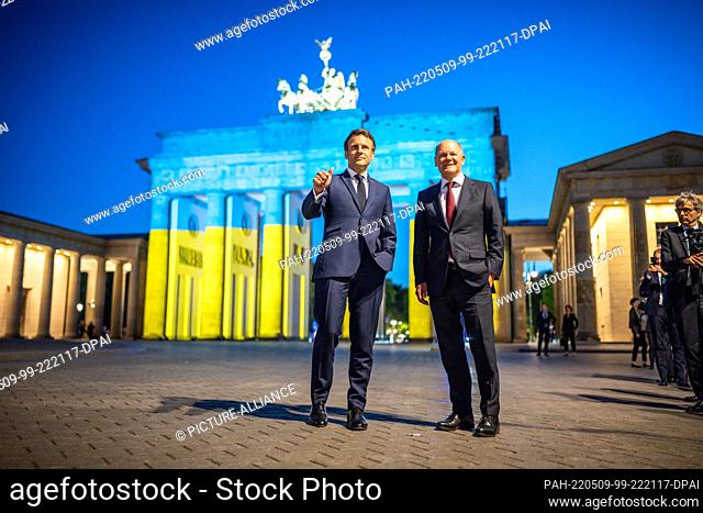 09 May 2022, Berlin: German Chancellor Olaf Scholz (r, SPD) and French President Emmanuel Macron stand in front of the Brandenburg Gate after a meeting