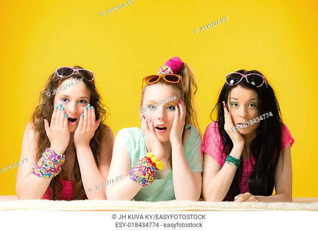 Three girls are having fun together, yellow background