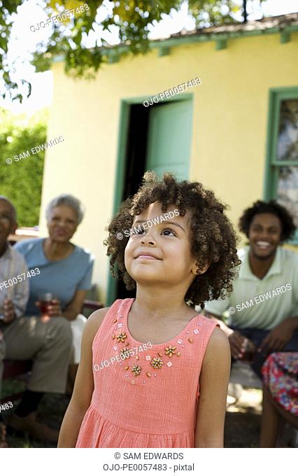 Young girl outdoors looking up with people in background