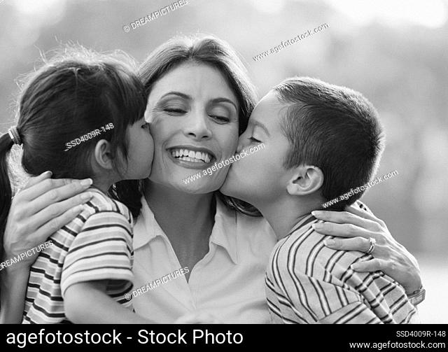 Two children kissing to their mother